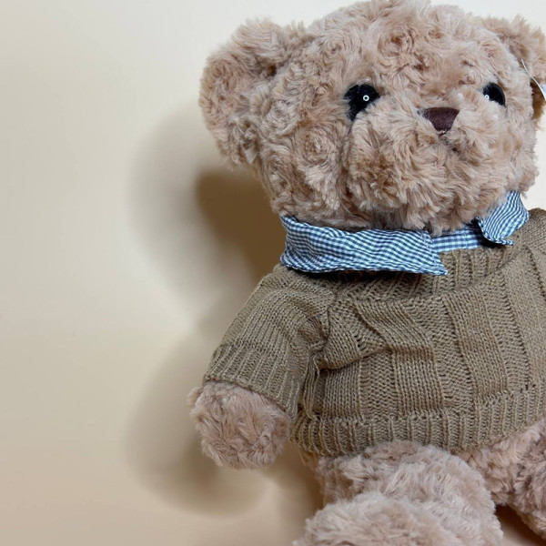 М’яка плюшева іграшка ведмедик у светрі коричневого кольору